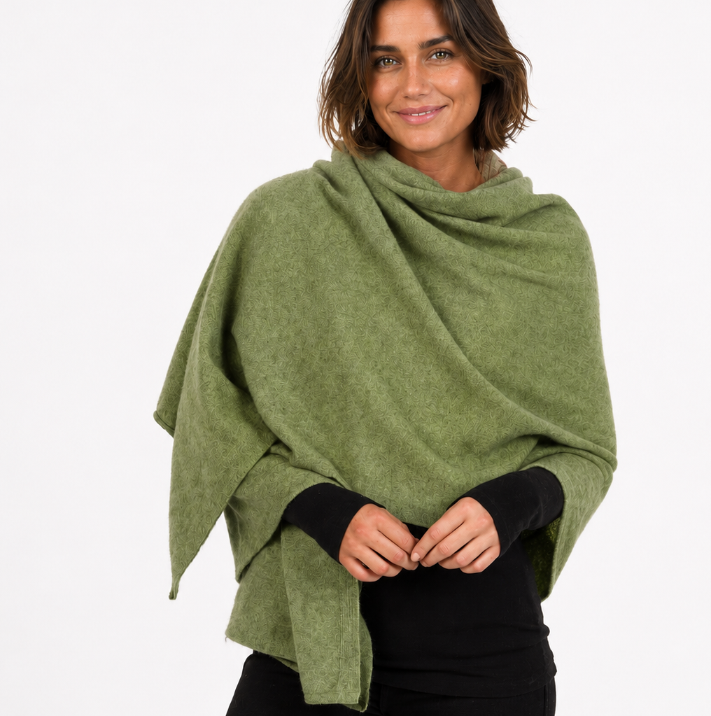 Woman wearing a green poncho over a black outfit on a white background